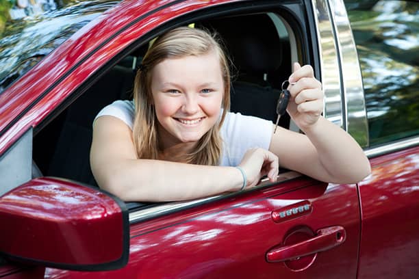 nuori nainen katsoo avonaisen autonikkunan läpi avain kädessään