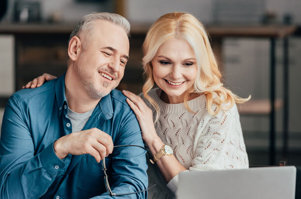 Onnelliset mies ja nainen katselevat tietokoneen näyttöä